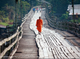 A monk crosses the Sangkhale River on the wooden bridge.