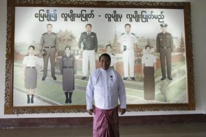 A minister stands in front of mural at the immigration office in Burma.